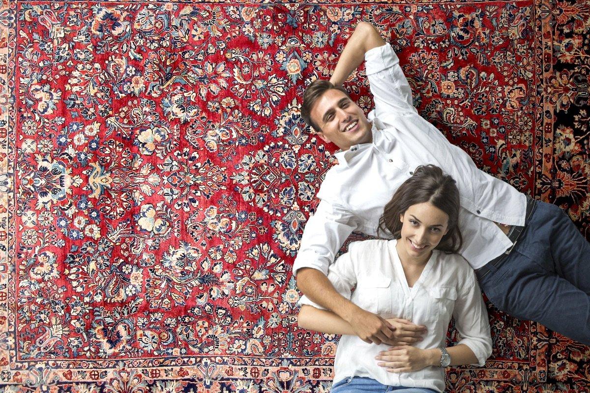 Koppel ontspant op klassiek rood Perzisch tapijt met bloemmotief