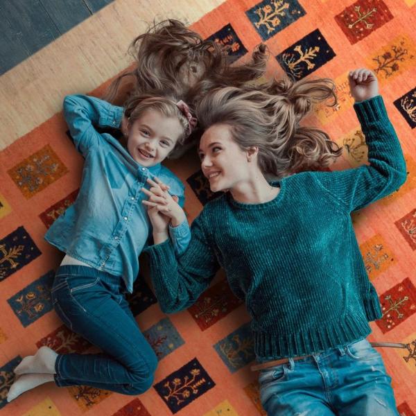 Mor og datter ligger og griner på et persisk Gabbeh Loribaft tæppe.