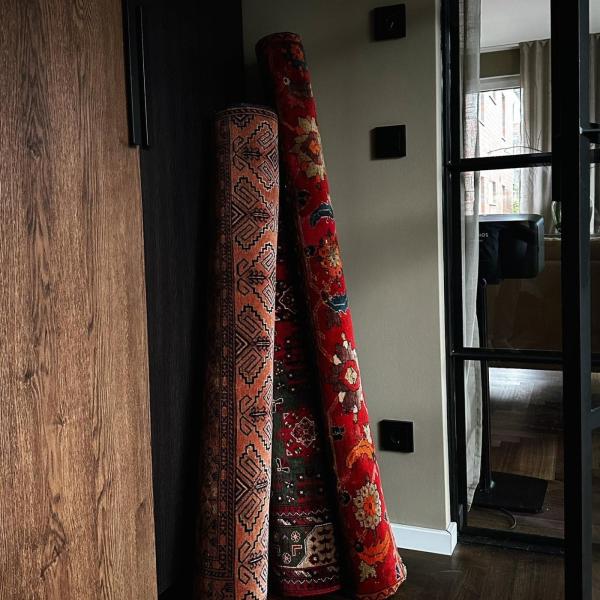 Rullede orientalske tæpper i røde nuancer i gangen