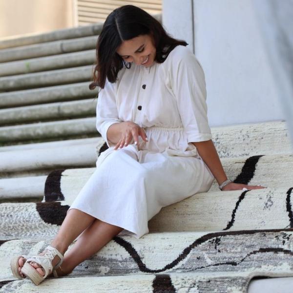 Designer, sidder lykkeligt på det håndknyttede berber tæppe i grå-hvid-sort.