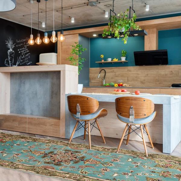Turkisfarvet orientalsk løber med blomstermønster som stilfuld accent i et åbent køkken-alrum.