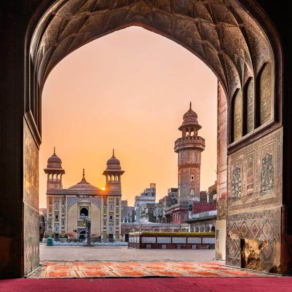 Kilátás a lahore-i Wazir-Khan-mecsetre napfelkeltével, imaszőnyegekkel az előtérben.