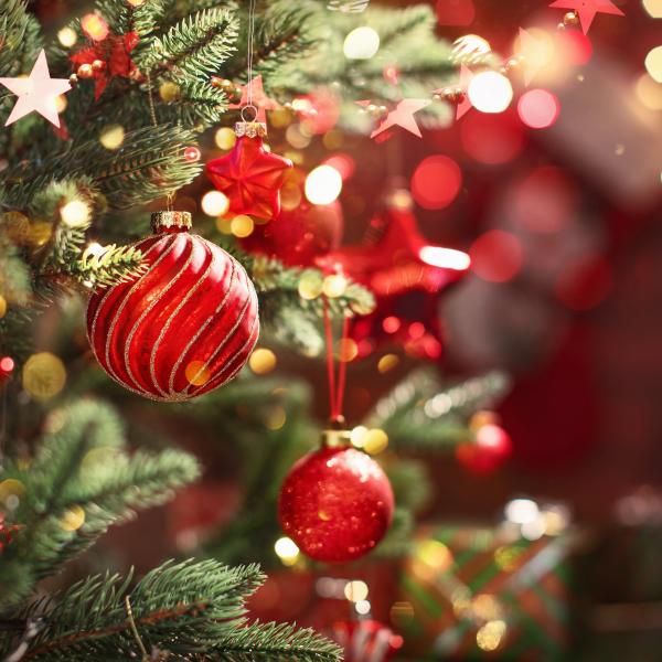 Részlet egy ünnepélyesen díszített karácsonyfáról piros gömbökkel és csillagokkal.