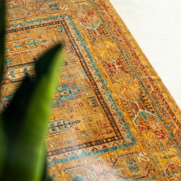 Részlet egy Arijana Klassik szőnyegről, sárga alapszínnel és kék nomád motívumokkal.