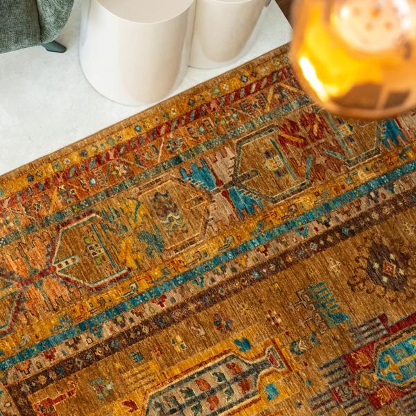 Közelkép az Arijana Klassik szőnyegről, hagyományos mintával arany- és kék árnyalatokban, modern W