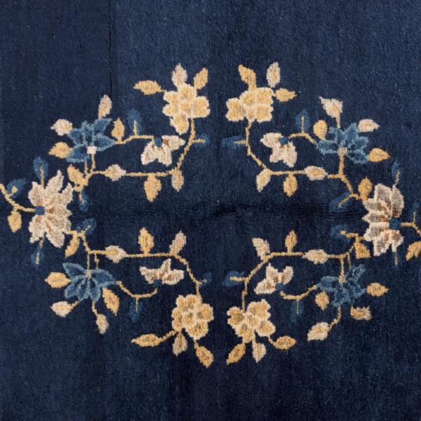 Nærbillede af bagsiden af et antikt Kina Peking tæppe med stiliserede bordurmotiver.