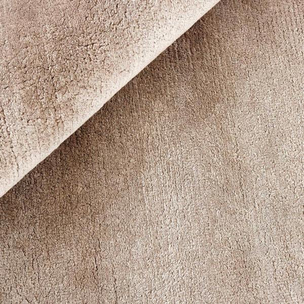 Tapis à poils longs beige avec une surface douce et dense et une texture discrète.