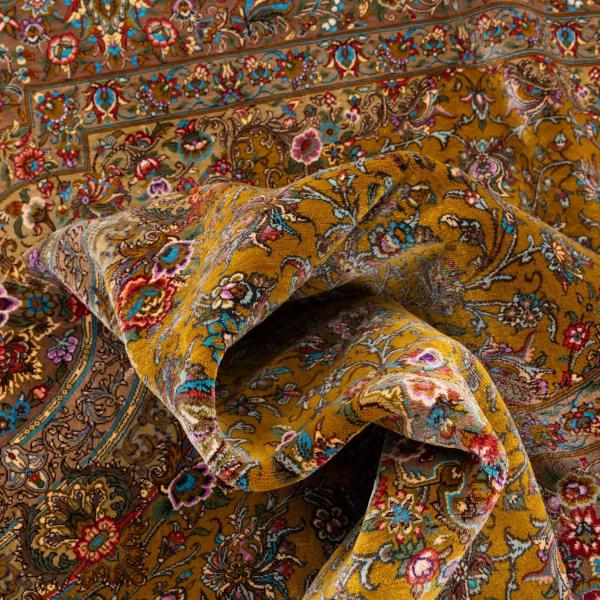 Közelkép egy kézzel csomózott selyem perzsa szőnyegről, finom virágmintákkal.