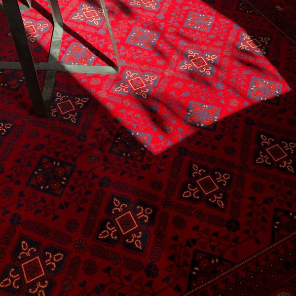 Detailní záběr afghánského koberce, který ukazuje jeho krásné tradiční vzory.