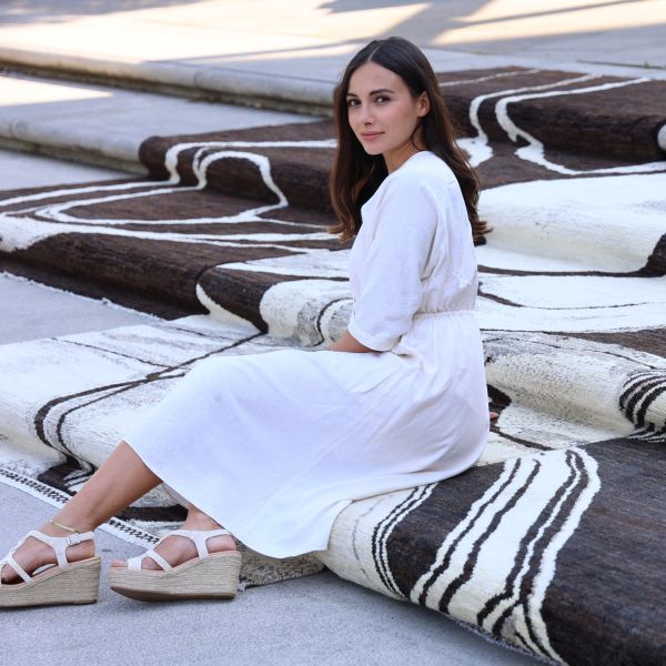 Designer Ela is sitting on the brown and white carpet from her collection.