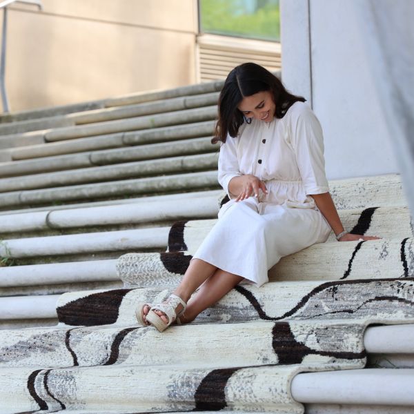 Designer, happily sitting on the hand-knotted Berber rug in grey, white and black.