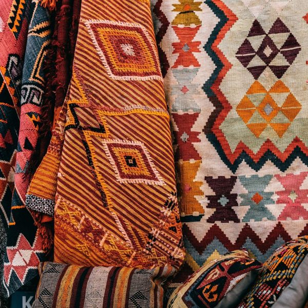 Close-up of a folded kilim rug in shades of blue, red, and orange with traditional geometric pattern