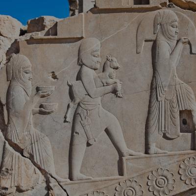 Detalje af et antikt stenskulptur med persiske figurer i traditionelt tøj.