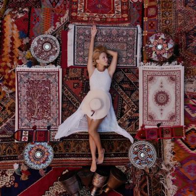 En kvinde ligger på et kunstnerisk tæppe-landskab af orientalske og persiske tæpper.