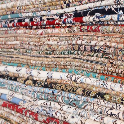 Une femme est allongée sur un paysage de tapis artistique composé de tapis orientaux et persans.