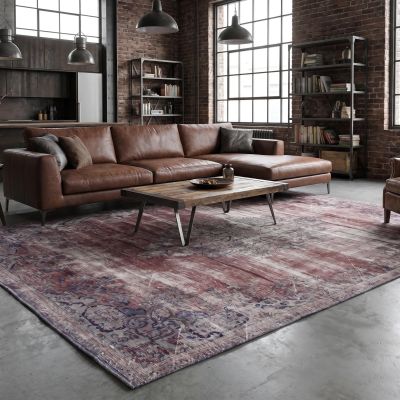 A loft living room in industrial style with a vintage rug and a brown leather sofa.