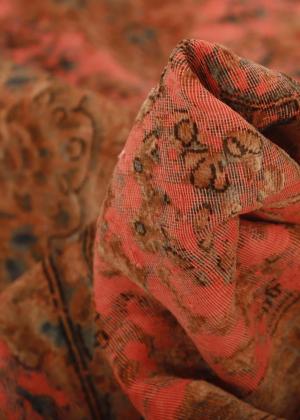 Közeli kép a vintage Kerman szőnyegről sötétvörös színben.